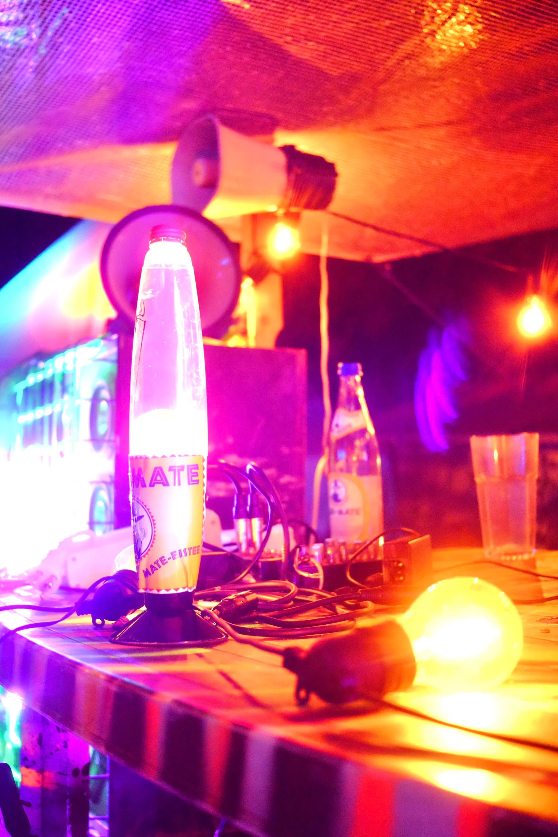 A desk at the WIP.bar at night. We can see a club mate bubble, several lights and 