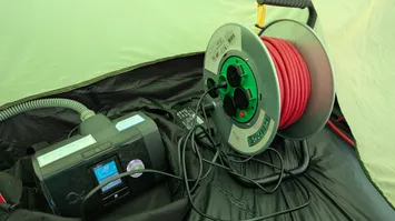 Fionas cpap unit in the tent.
We can see the rest of the cable still on the spool next to it.
This would do fine to support her sleep.