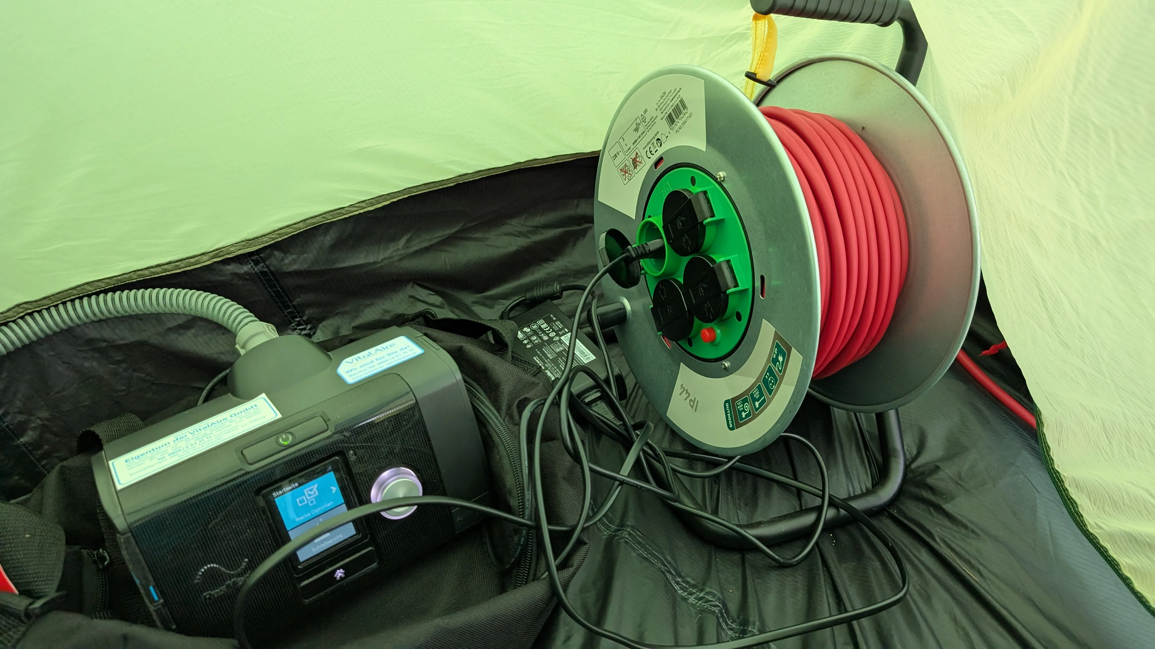 Fionas cpap unit in the tent.
We can see the rest of the cable still on the spool next to it.
This would do fine to support her sleep.